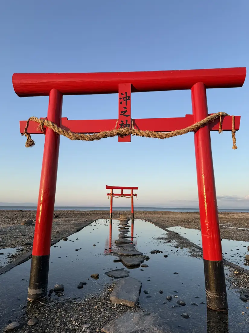 The sea torii standing on the tidal flats at low tide, a stone path leading out to the sea